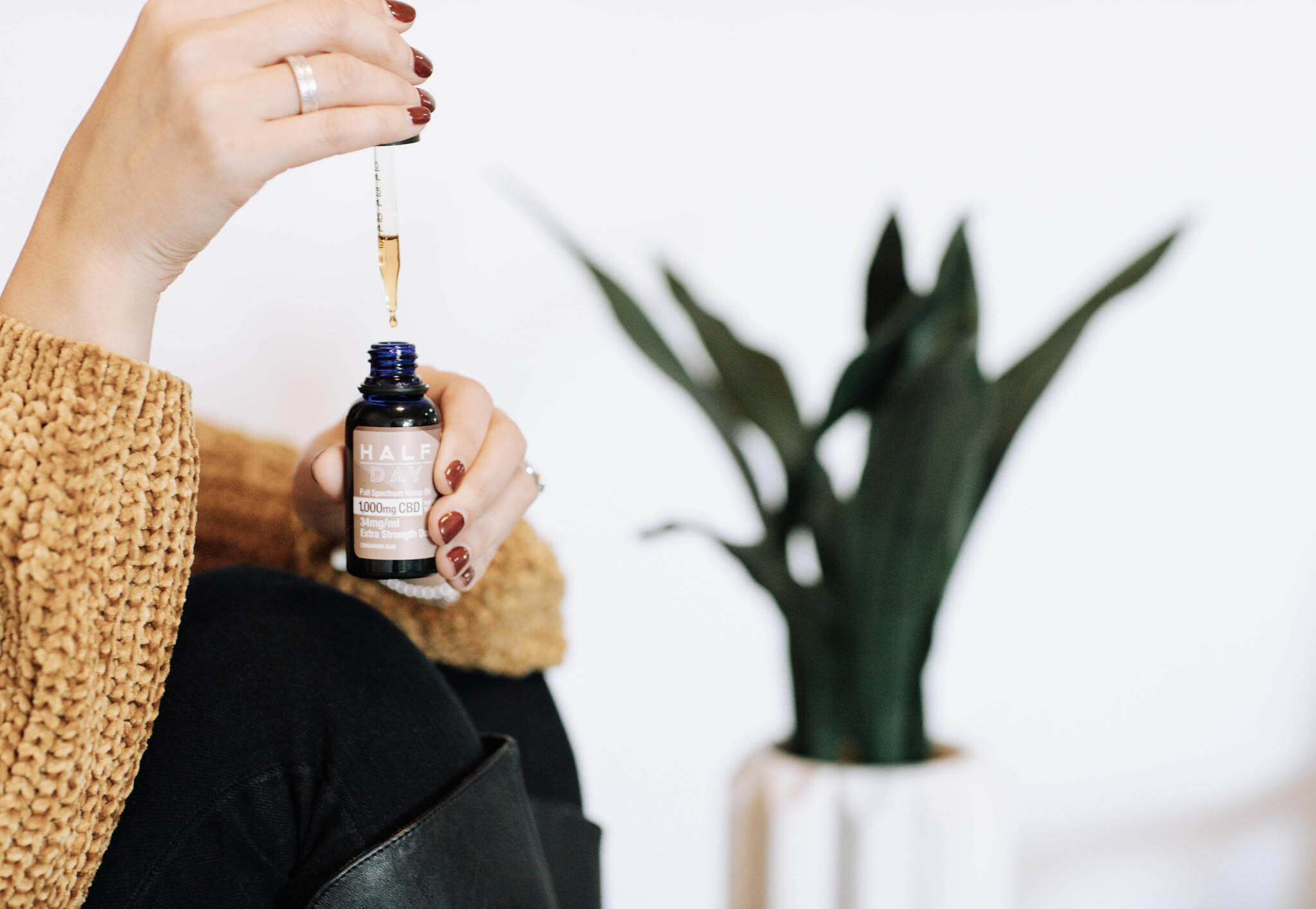 hands using eyedropper to get CBD oil out of a bottle